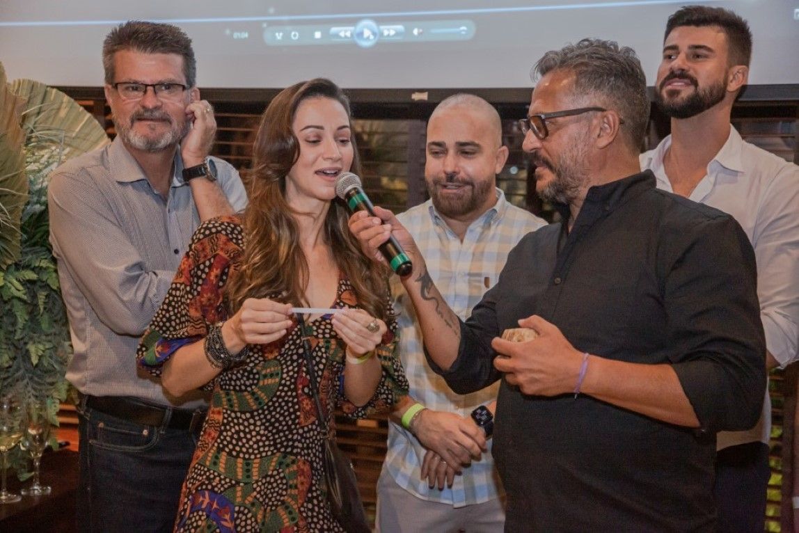 Um grupo de pessoas está em volta de uma mulher segurando um microfone.