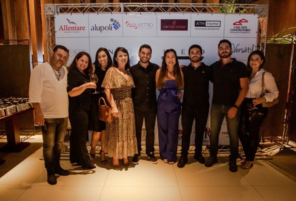 Um grupo de pessoas está posando para uma foto em frente a uma parede com logotipos.