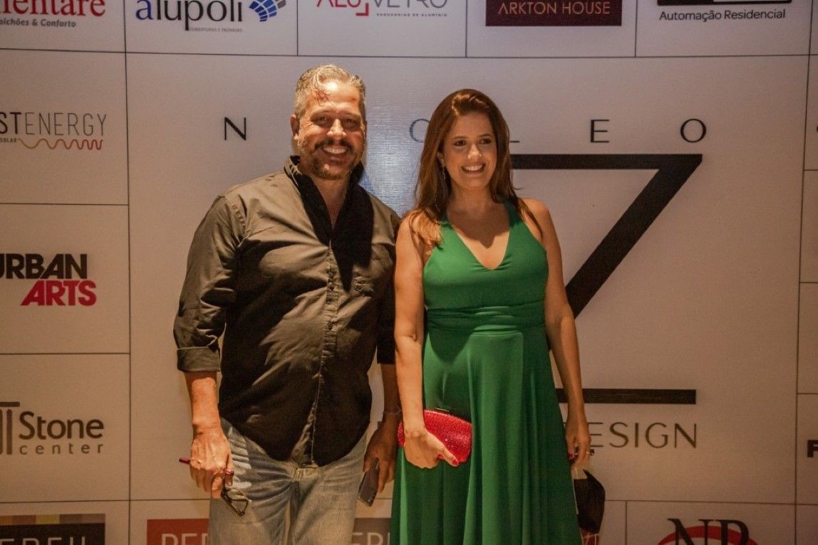 Um homem e uma mulher estão posando para uma foto em frente a uma parede com logotipos.