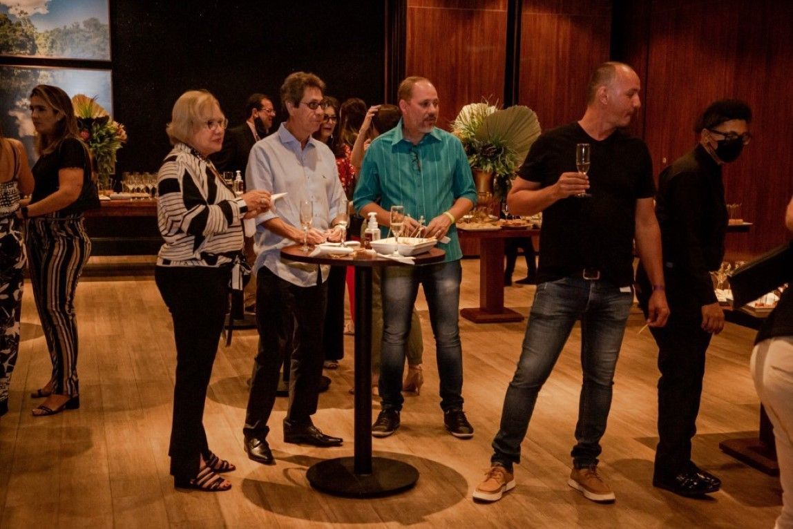 Um grupo de pessoas está em pé ao redor de uma mesa em uma sala.