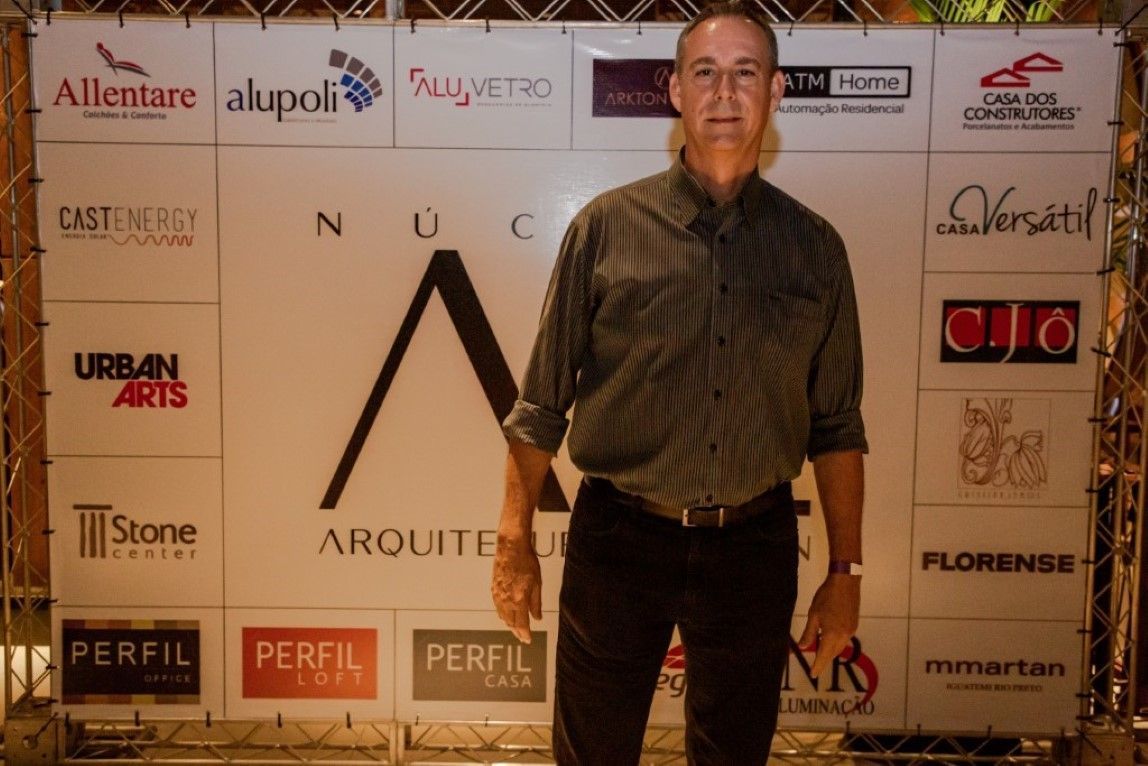 Um homem parado em frente a uma parede com logotipos nela