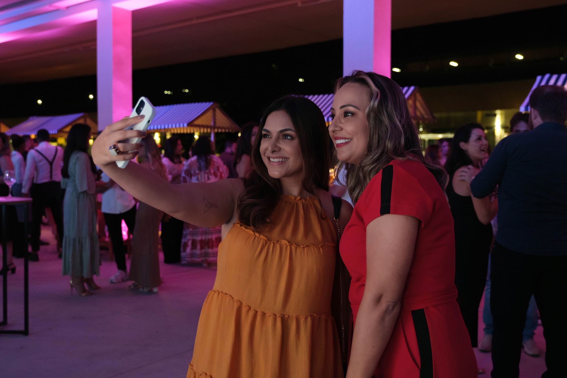 Duas mulheres estão tirando uma selfie juntas em uma festa.