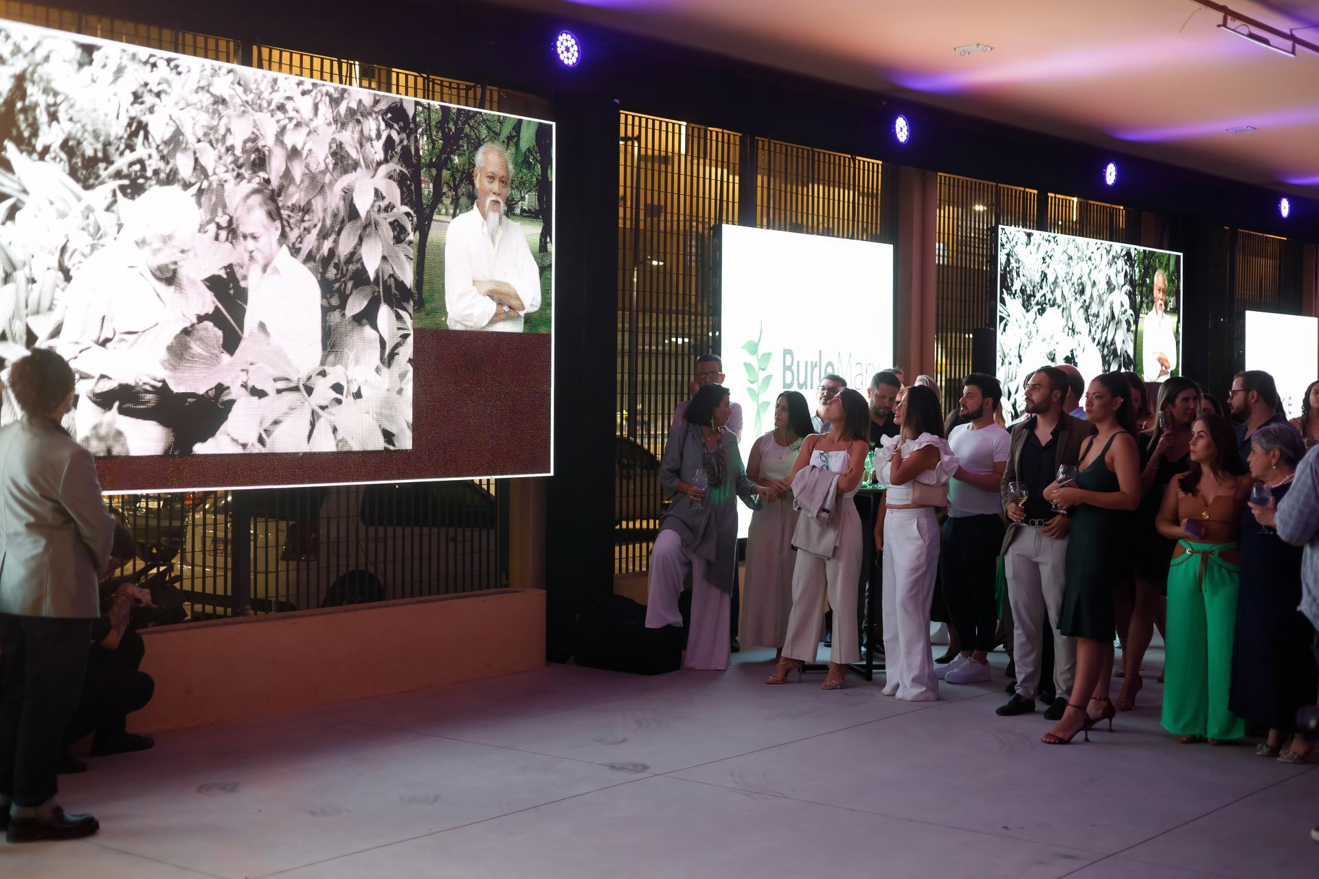 Um grupo de pessoas está em pé em frente a uma tela grande.