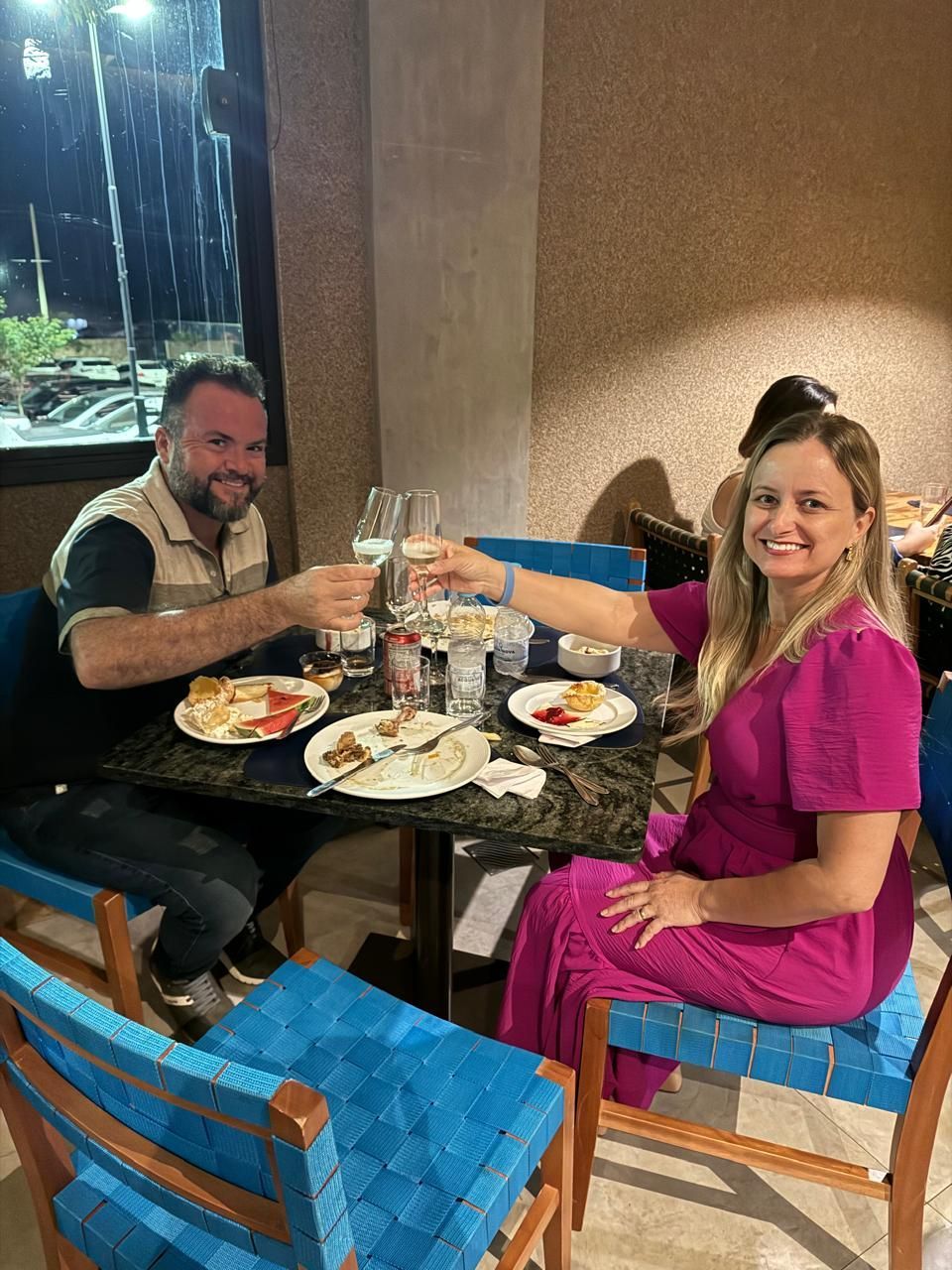 Um homem e uma mulher estão sentados à mesa com pratos de comida.