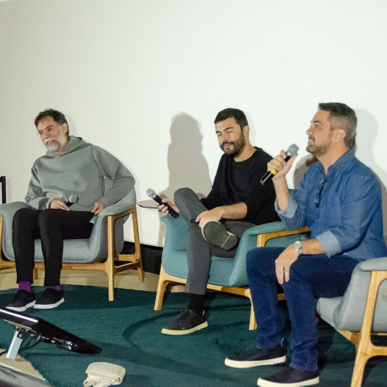 Um grupo de homens está sentado em um sofá em frente a uma estante de livros
