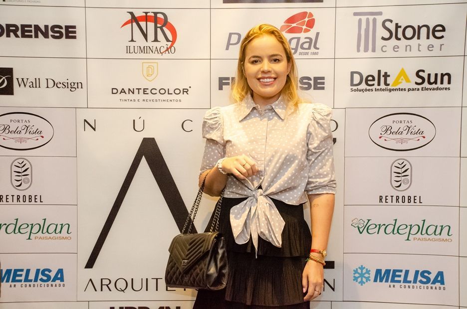 Uma mulher parada em frente a uma parede com logotipos