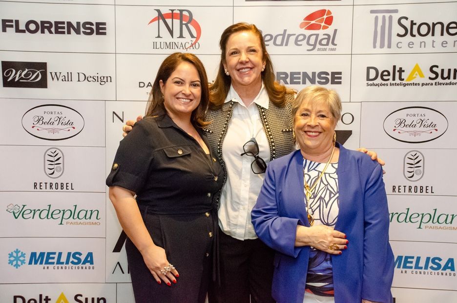 Três mulheres posam para uma foto em frente a uma parede que diz florense