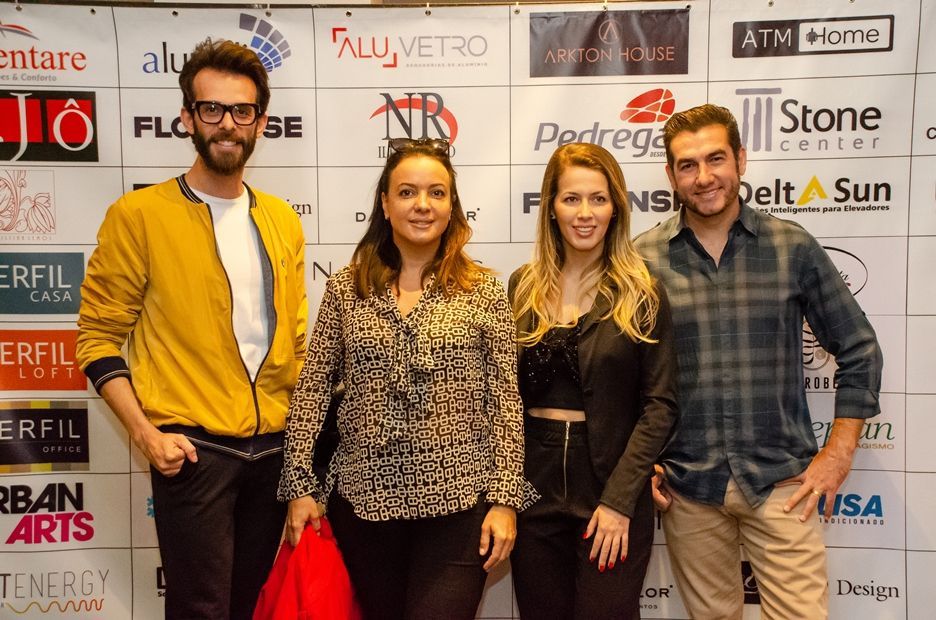 Um grupo de pessoas está posando para uma foto em frente a uma parede com logotipos