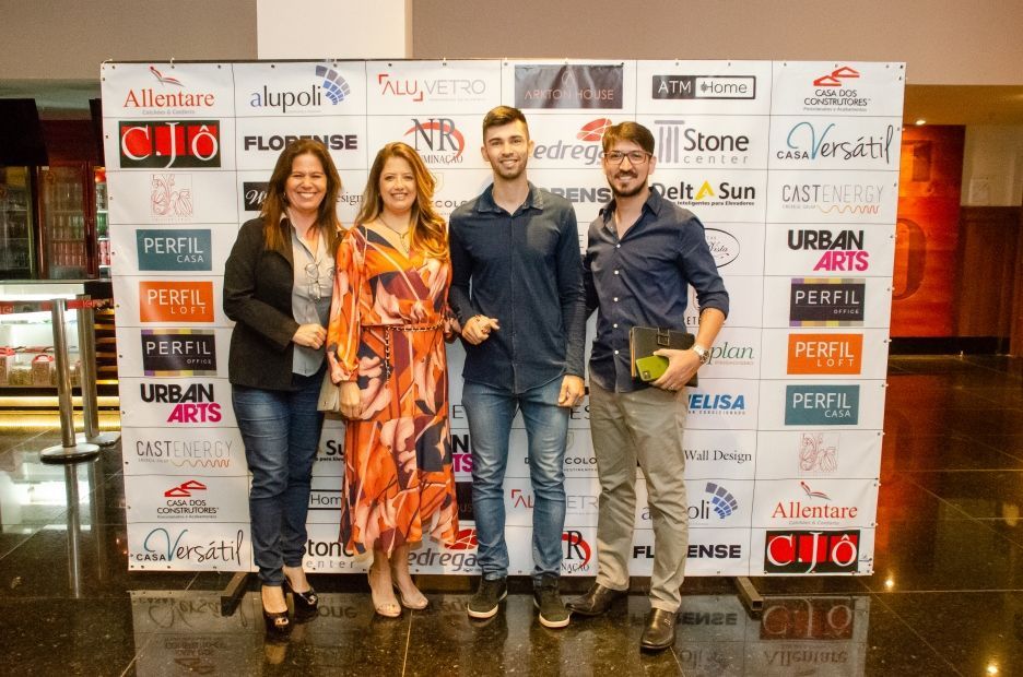 Um grupo de pessoas em pé em frente a uma parede com logotipos nela.