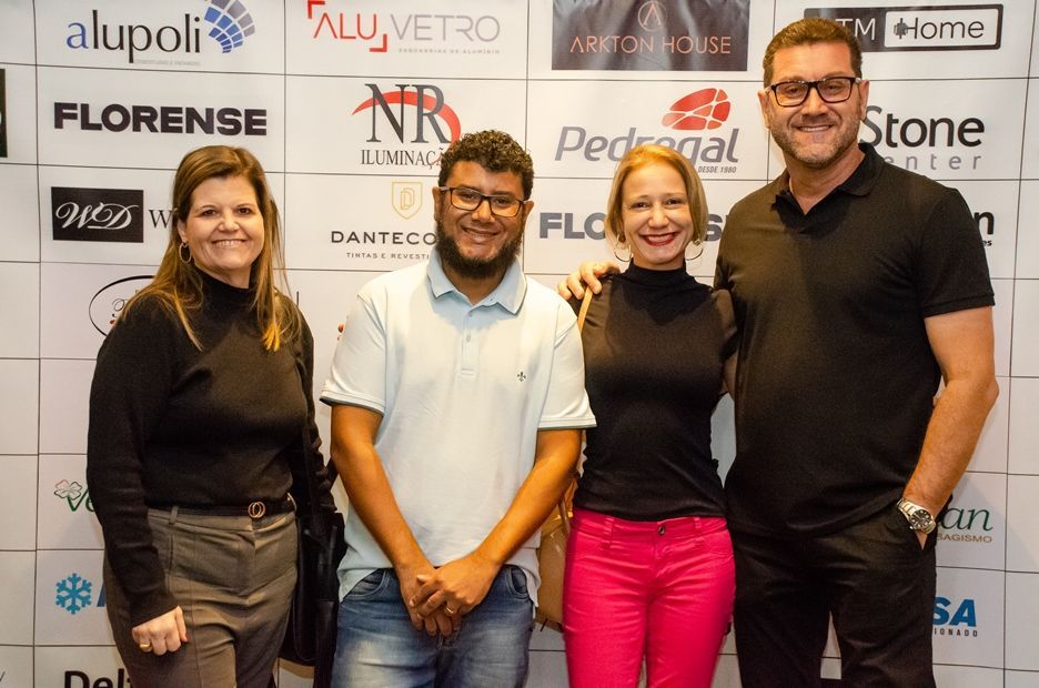 Um grupo de pessoas está posando para uma foto em frente a uma parede com logotipos.
