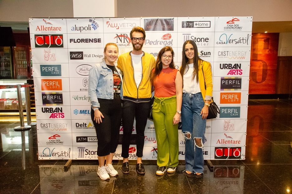 Um grupo de pessoas em pé em frente a uma parede com logotipos nela.