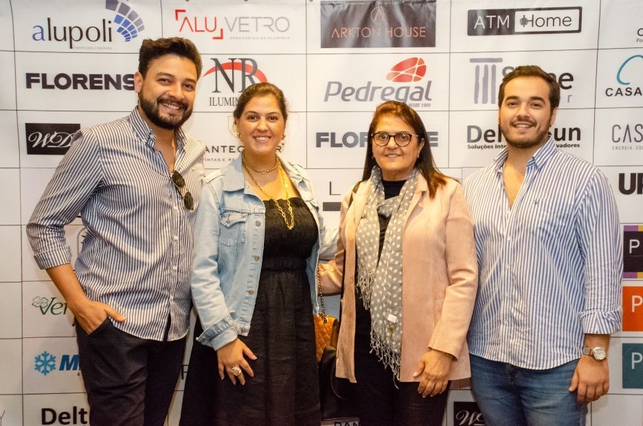 Um grupo de pessoas está posando para uma foto em frente a uma parede com logotipos.