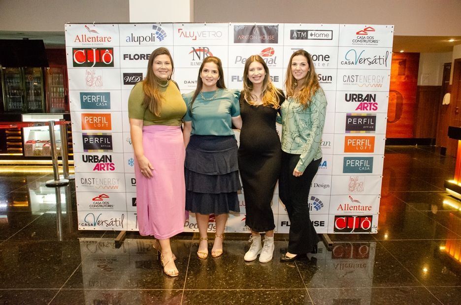 Um grupo de mulheres está posando para uma foto em frente a uma parede com logotipos.