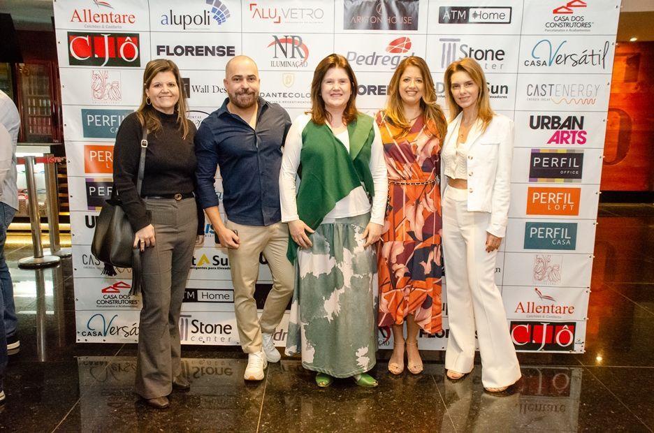 Um grupo de pessoas está posando para uma foto em frente a uma parede com logotipos.