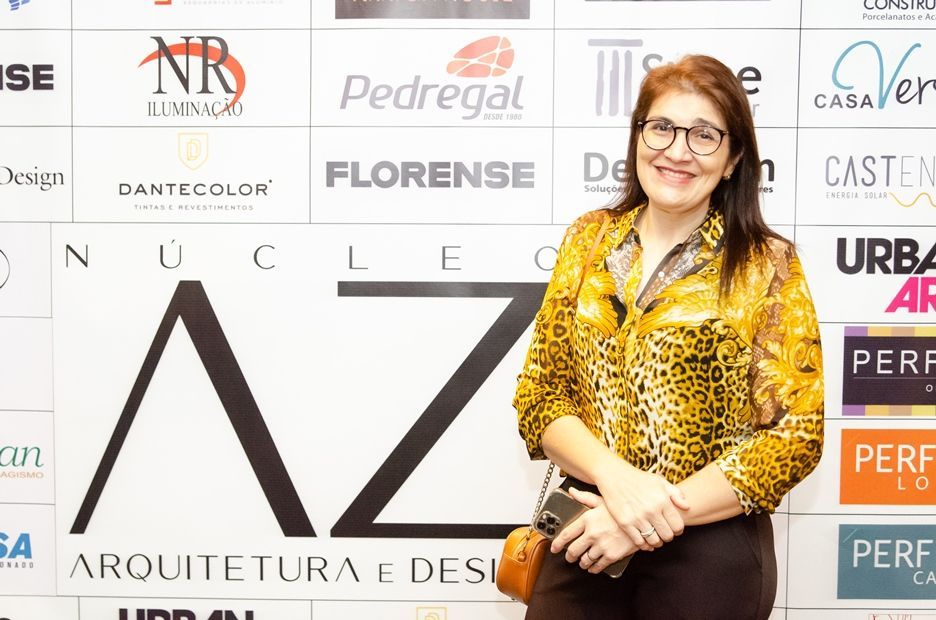 Uma mulher está parada em frente a uma parede com logotipos.