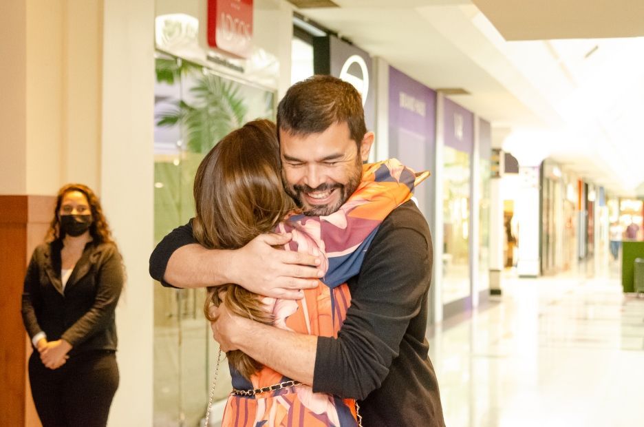 Um homem está abraçando uma mulher em um shopping.