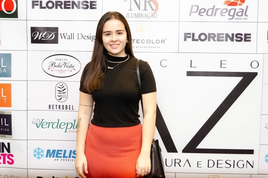 Uma mulher está parada em frente a uma parede com logotipos.