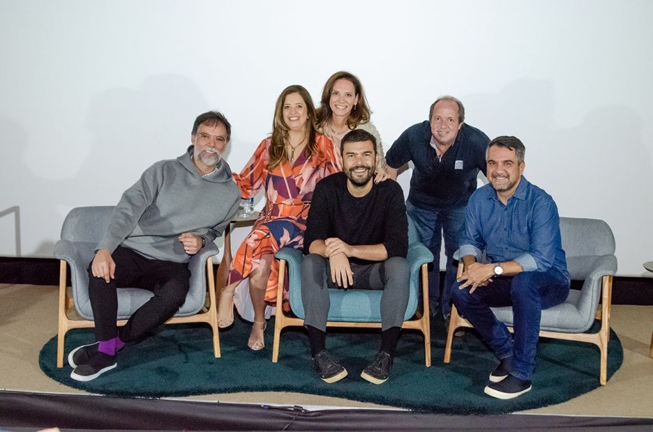 Um grupo de pessoas está posando para uma foto enquanto estão sentadas em um sofá.