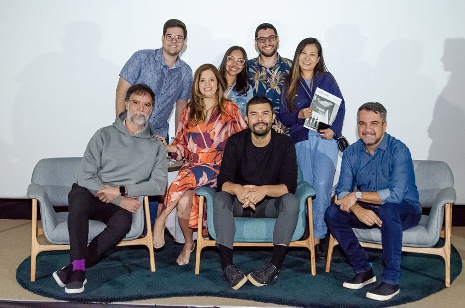 Um grupo de pessoas está posando para uma foto enquanto estão sentadas em um sofá.