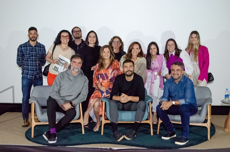 Um grupo de pessoas está posando para uma foto enquanto estão sentadas em um sofá.