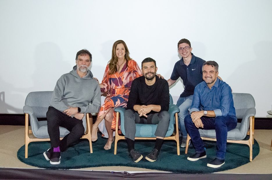 Um grupo de pessoas está posando para uma foto enquanto estão sentadas em um sofá.