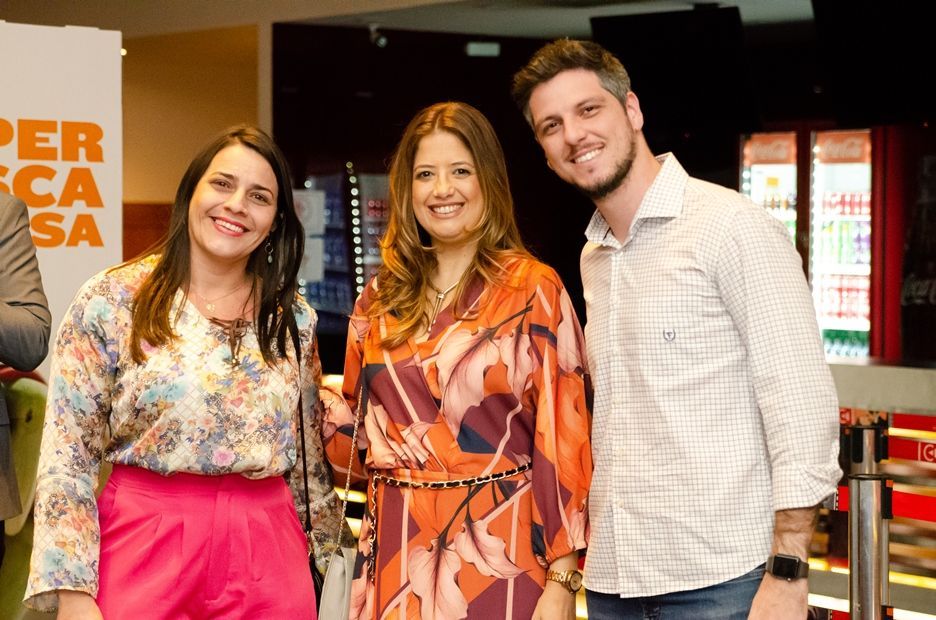 Três pessoas estão posando para uma foto juntas em uma sala.