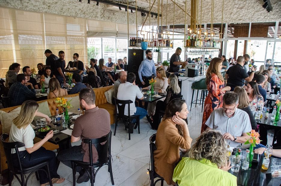 Um grande grupo de pessoas está sentado em mesas em um restaurante.