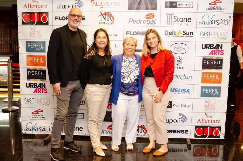 Um grupo de pessoas em pé em frente a uma parede com logotipos nela.