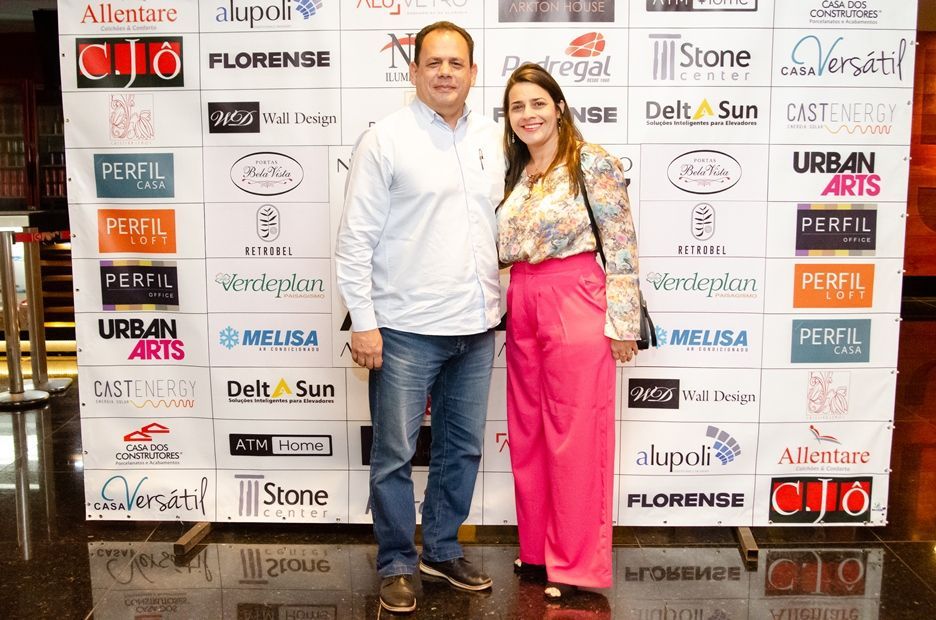 Um homem e uma mulher estão posando para uma foto em frente a uma parede coberta de logotipos.