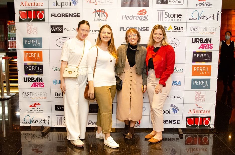 Um grupo de mulheres está posando para uma foto em frente a uma parede com logotipos.