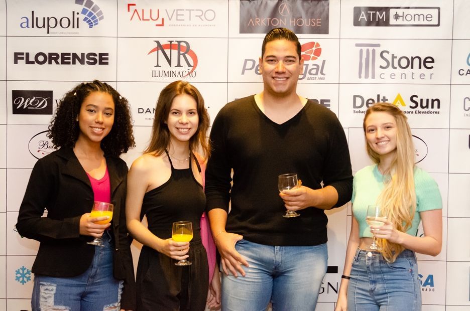 Um grupo de pessoas de pé, uma ao lado da outra, segurando taças de vinho.