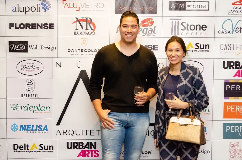 Um homem e uma mulher estão em pé em frente a uma parede com logotipos.