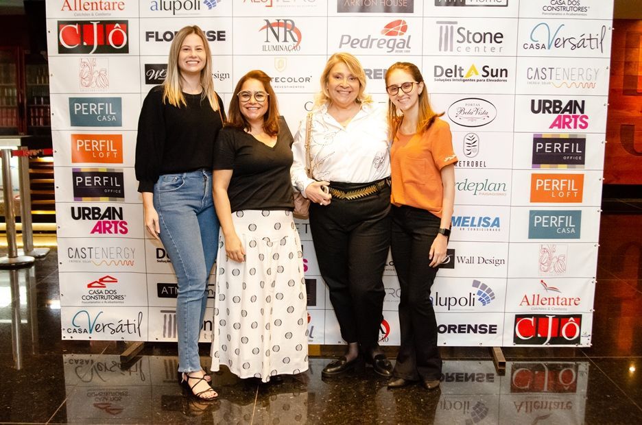 Um grupo de mulheres está posando para uma foto em frente a uma parede com logotipos.