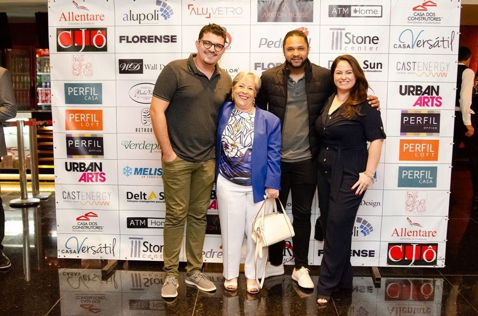 Um grupo de pessoas está posando para uma foto em frente a uma parede com logotipos.