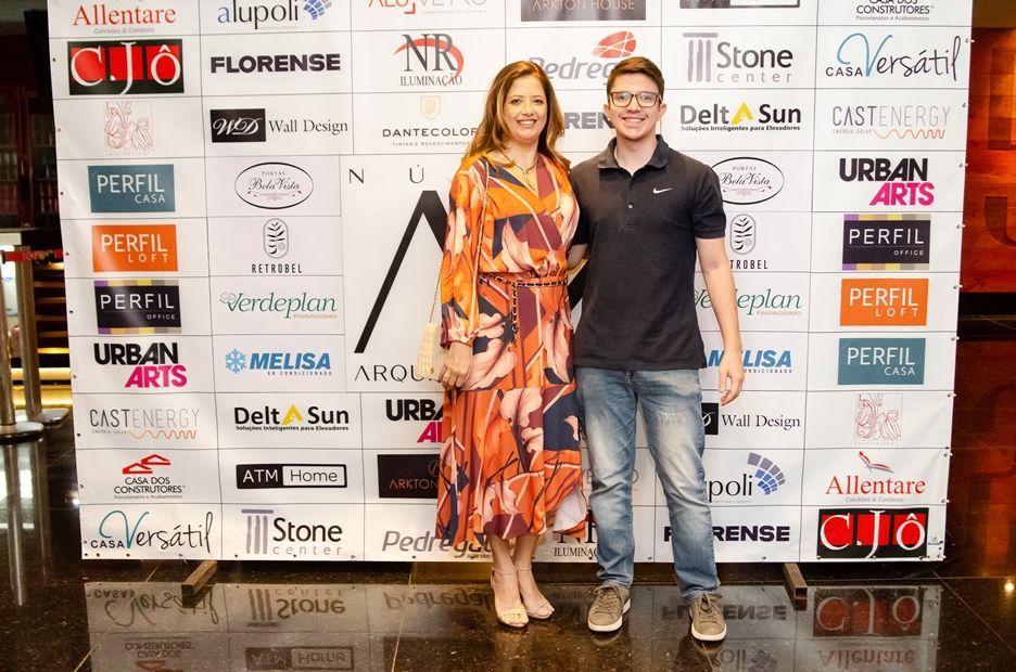 Um homem e uma mulher estão posando para uma foto em frente a uma parede coberta de logotipos.