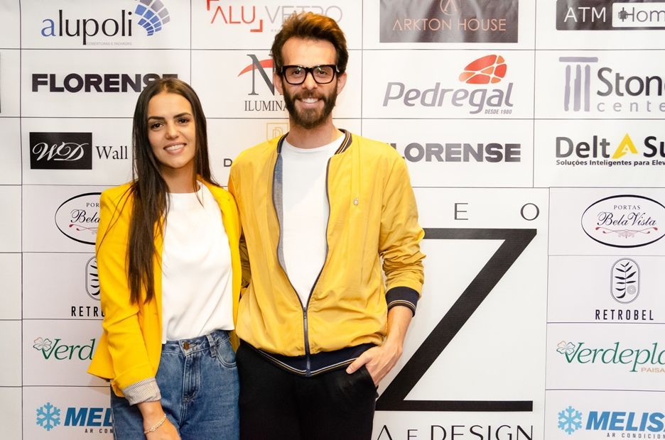 Um homem e uma mulher estão posando para uma foto em frente a uma parede de logotipos.