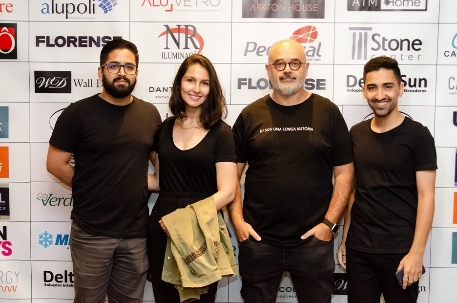 Um grupo de pessoas posando para uma foto em frente a uma parede com logotipos