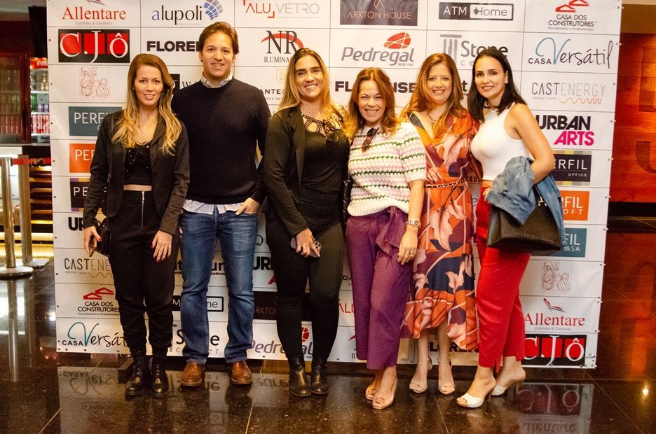 Um grupo de pessoas em pé em frente a uma parede com logotipos nela