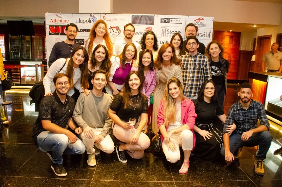 Um grupo de pessoas está posando para uma foto em um cinema.