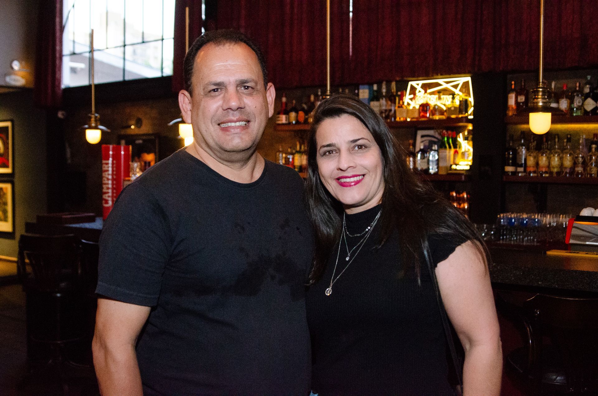 Um homem e uma mulher estão posando para uma foto em um bar.