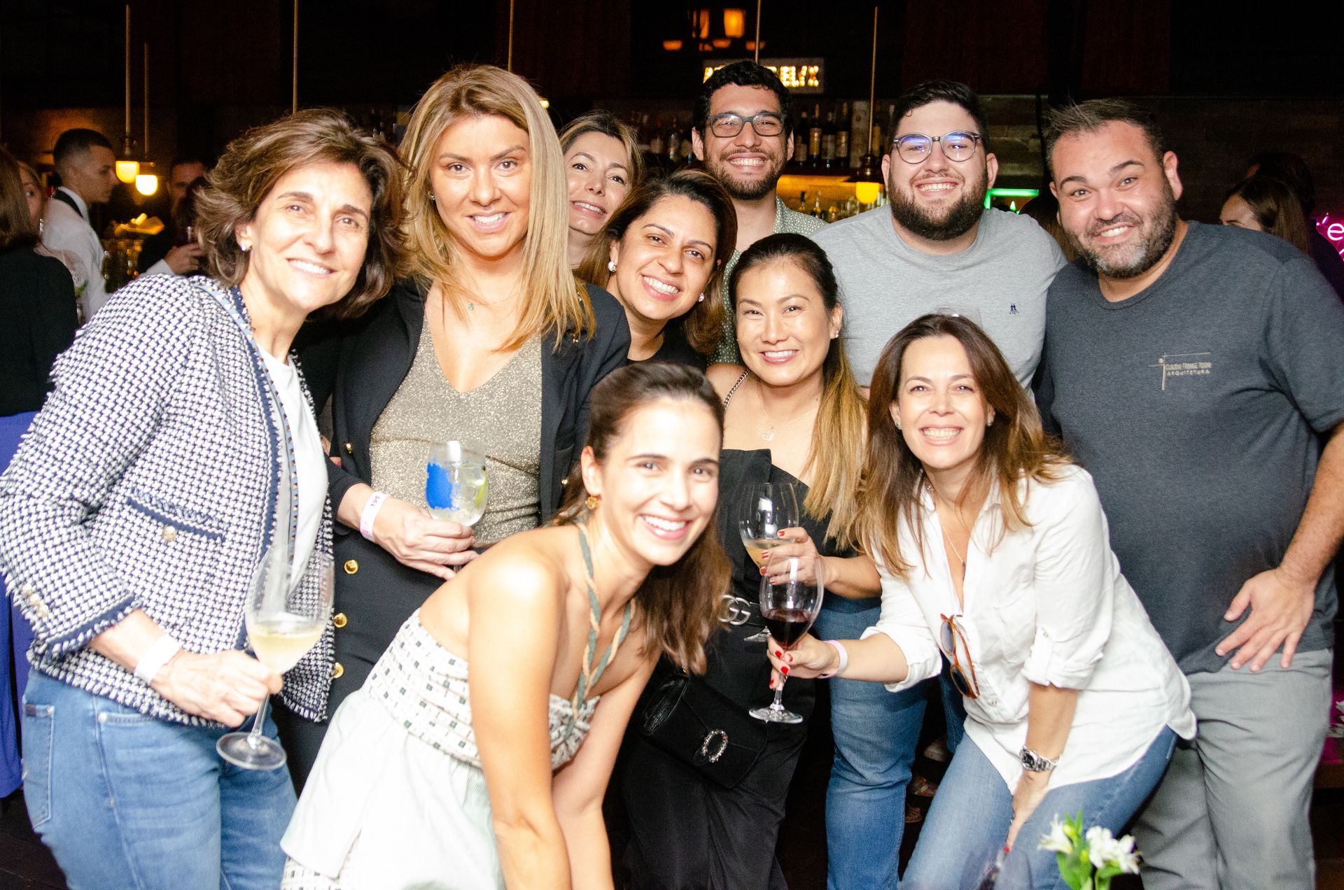 Um grupo de pessoas está posando para uma foto segurando taças de vinho.