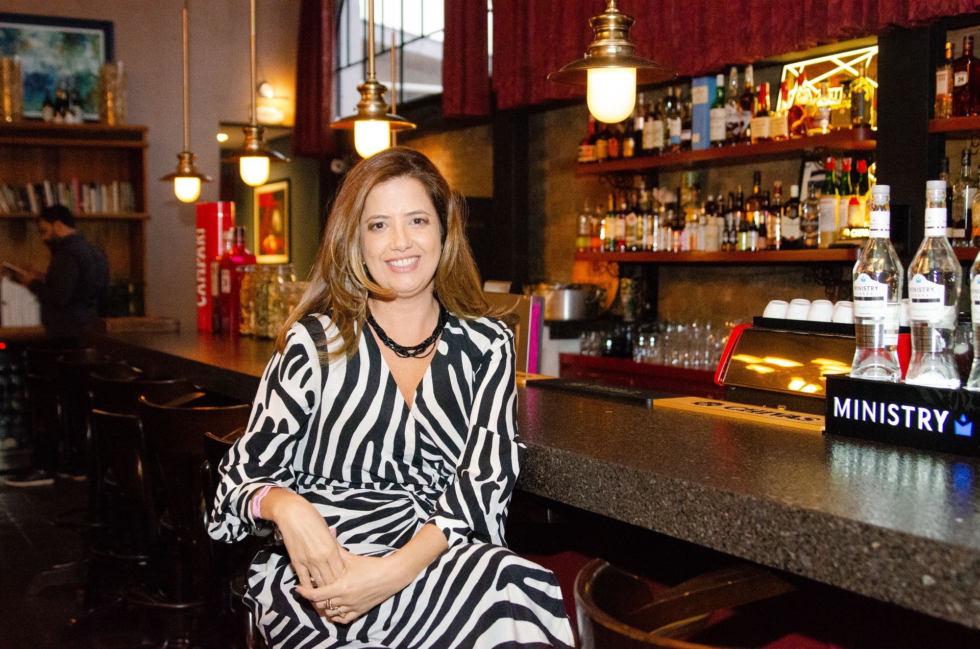 Uma mulher com um vestido estampado de zebra está sentada em um bar.
