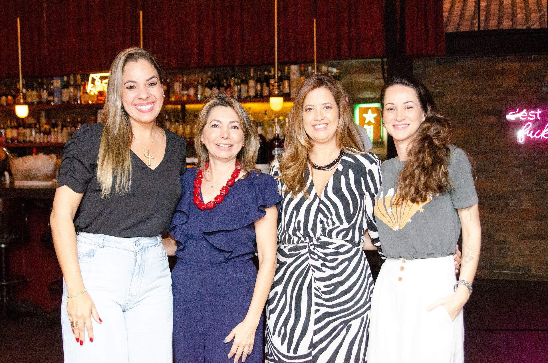 Quatro mulheres estão posando para uma foto em frente a um bar.