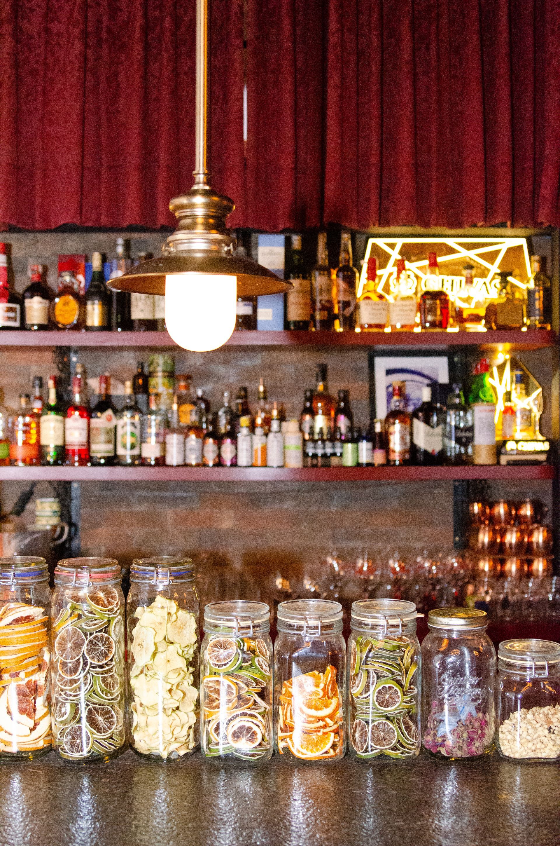 Um bar com potes de comida e garrafas nas prateleiras.