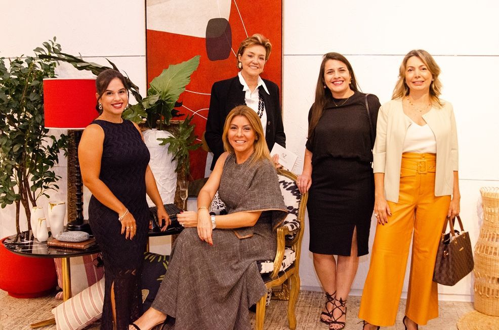 Um grupo de mulheres está posando para uma foto em frente a uma pintura.