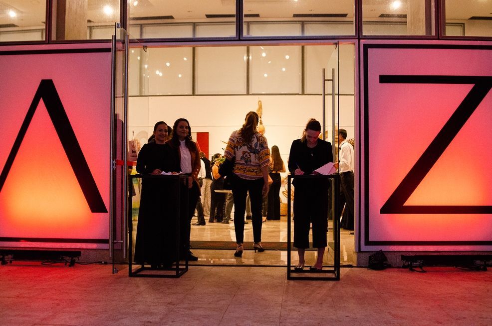 Um grupo de pessoas em pé na frente de um prédio com a letra z escrita nele