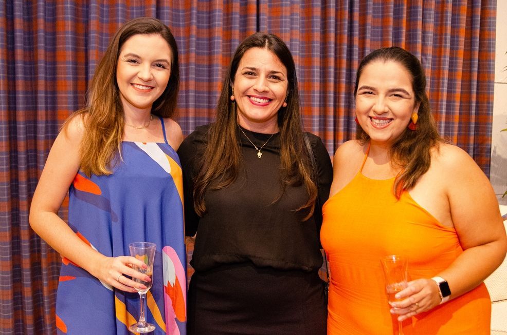 Três mulheres estão posando para uma foto juntas segurando taças de vinho.