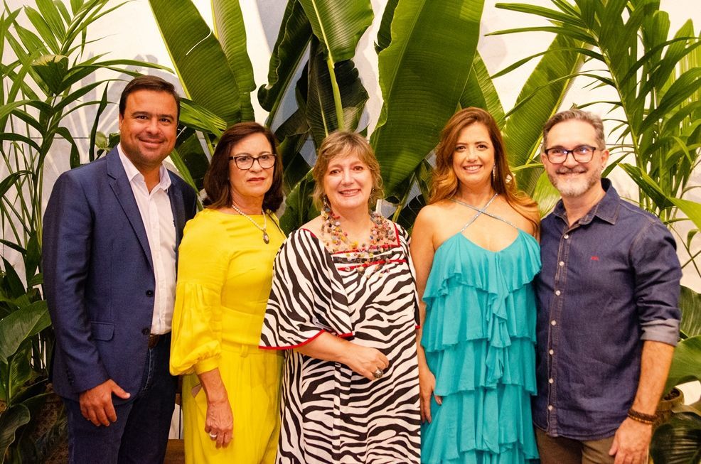 Um grupo de pessoas está posando para uma foto em frente às plantas.