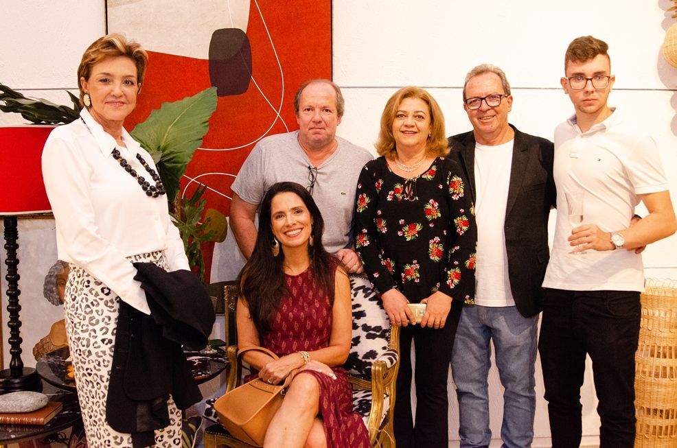 Um grupo de pessoas está posando para uma foto em frente a uma pintura.