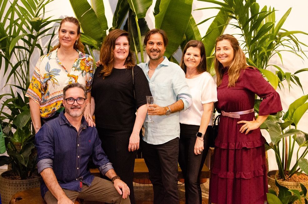 Um grupo de pessoas está posando para uma foto em frente às plantas.